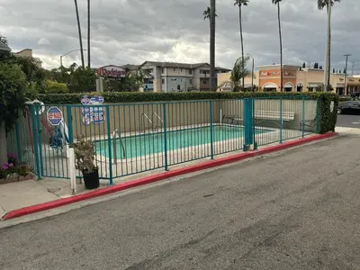 a fence with a swimming pool on the side of a street at Crzy 8 Motel in Orange