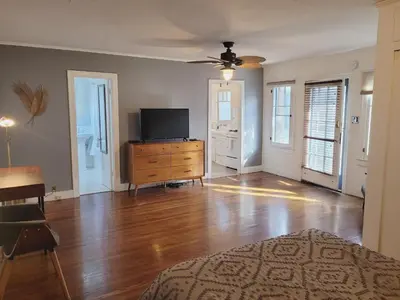 an empty living room with a tv and a wooden dresser at Spacious Studio Six in Hollywood! in Los Angeles