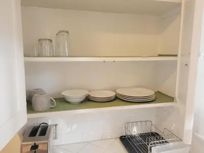 a kitchen with plates and bowls on a shelf at Spacious Studio Six in Hollywood! in Los Angeles
