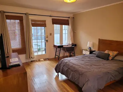 a bedroom with a bed and a desk and windows at Beautiful Bungalow Five in Hollywood! in Los Angeles