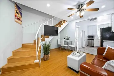 a living room with a couch and a tv and a staircase at Elegant Beachside 2 Bed 2 Bath in Long Beach