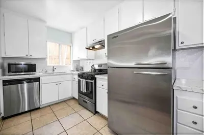 a kitchen with white cabinets and a stainless steel refrigerator at Elegant Beachside 2 Bed 2 Bath in Long Beach