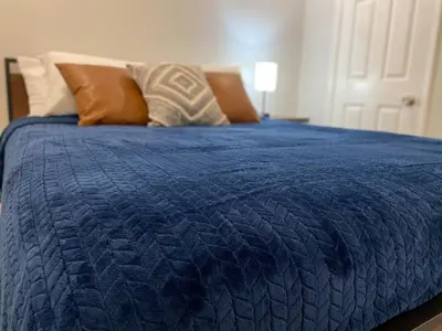 a bed with a blue comforter and pillows on it at HubCityJewel in Compton