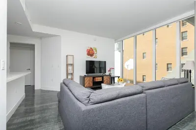 a living room with a gray couch and a tv at Stylish 3BR High-Rise with Pool, Hot Tub & Rooftop Views in Los Angeles