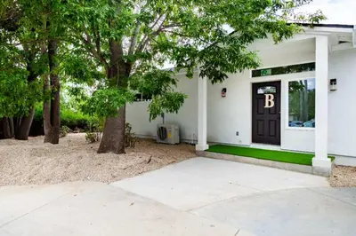 a white house with a black door and trees at Cozy 2BR Home Mountain Views Pet Friendly in Thousand Oaks