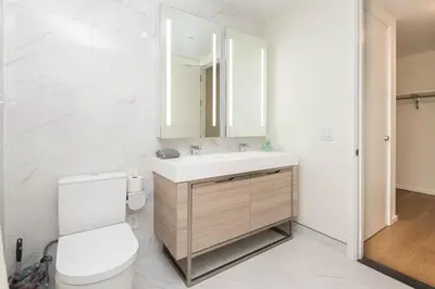 a bathroom with a toilet and a sink and a mirror at Cozy 3BR High Rise with Pool with great views in Los Angeles
