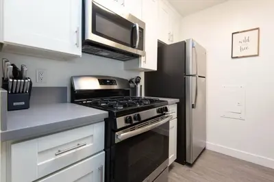 a kitchen with a stove and a stainless steel refrigerator at Snazzy 2 Bedroom Pad with Rooftop Pool and Hollywood Sign View in Los Angeles