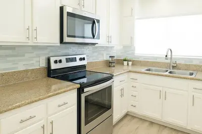 a kitchen with white cabinets and a stove and a microwave at Spacious 2BR Townhouse - 3 Queens - Sleeps 8 in Redondo Beach