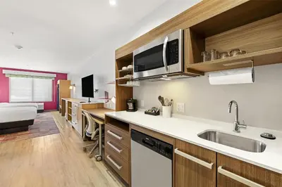 a kitchen with a sink and a bed in a room at Home2 Suites By Hilton Riverside Downtown in Riverside