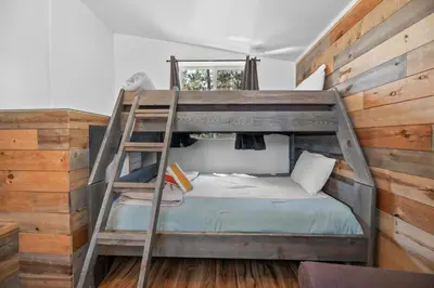 a bunk bed with a ladder in a room at StoneHauz was built in 1926! It's a REAL CABIN! in Big Bear Lake
