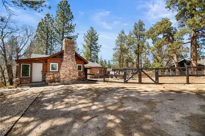 a home in the woods with a fence at StoneHauz was built in 1926! It's a REAL CABIN! in Big Bear Lake
