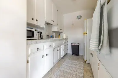 a kitchen with white cabinets and a refrigerator at Steps to Ocean Bliss in Long Beach