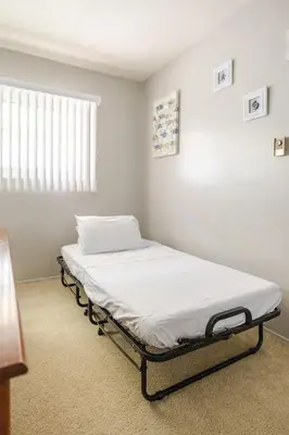a hospital bed in a room with a window at Steps to Ocean Bliss in Long Beach