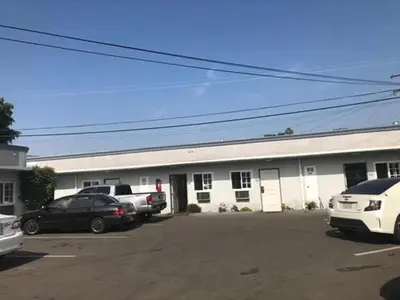a large white building with cars parked in a parking lot at El Grande Motel in South Gate