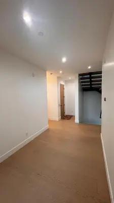 an empty living room with white walls and wood floors at Ocean Vista in Palos Verdes Estates