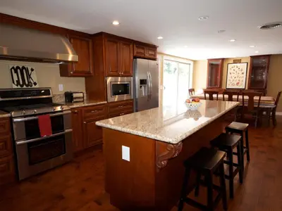 a kitchen with wooden cabinets and a large island with bar stools at F-28 The Wonderland House in Anaheim