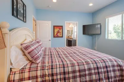 a bedroom with a bed with a plaid blanket and a tv at F-32 La Casa de Mickey in Anaheim