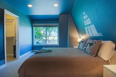 a blue bedroom with a bed and a window at F-15 Haunted Mansion in Anaheim