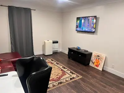 a living room with a couch and a tv on the wall at Beautiful 2-bedroom downstairs unit by LAX, SoFi, BMO, USC in Los Angeles