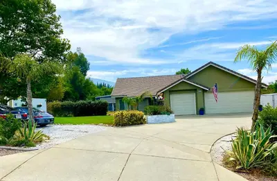 a house with a palm tree and a driveway at Cozy Container in Devore Heights, California, for Glamping Getaways on Route 66 in Devore Heights