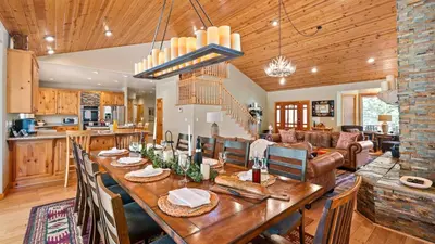 a dining room and living room with a large wooden table at Sleeps 27 2 Homes Near the Lake Hot Tub Views Castle Glen Estates in Big Bear Lake