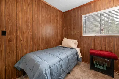 a bedroom with wooden walls and a bed and a window at Bluebird Cabin, Indoor Fireplace, Next to Lake! in Green Valley Lake