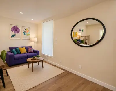 a living room with a purple couch and a round mirror at Boutique KTown Stays With Breathtaking Rooftop Views in Los Angeles