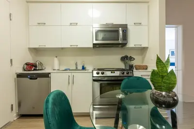a kitchen with white cabinets and a table with green chairs at Elegant & Charming 2BR Apartment in Glendale