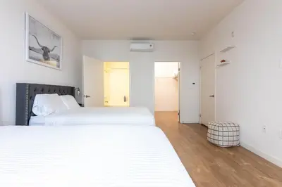 two beds in a bedroom with white walls and wooden floors at Lovely and Modern Apartment in Glendale
