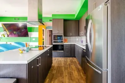a kitchen with gray cabinets and a refrigerator at Colorful penthouse near DTLA in Los Angeles