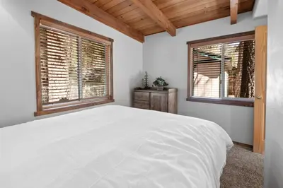 a bedroom with a white bed and two windows at Comstock Cabin by Rather Be Properties in Big Bear Lake