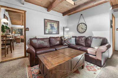 a living room with a brown leather couch and a table at Comstock Cabin by Rather Be Properties in Big Bear Lake