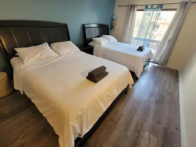 two beds in a hotel room with a towel on them at Great Location Double Queen Bed Unit in Los Angeles