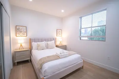 a white bedroom with a bed and two lamps at Stylish Private Room by Downtown LA in Los Angeles