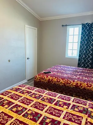 a bedroom with two beds and a window at Plaza Hotel Gardena in Gardena