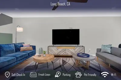 a living room with a blue couch and a flat screen tv at Chic 4B2B Townhome Private Pool in Long Beach