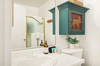a bathroom with a sink and a blue cabinet above a toilet at Summit Slope Side in Big Bear Lake