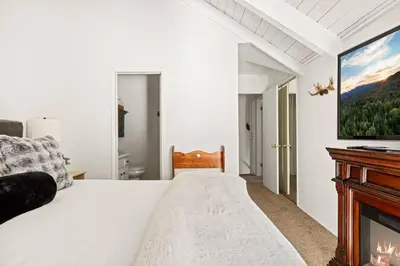 a white bedroom with a bed and a fireplace at Summit Slope Side in Big Bear Lake