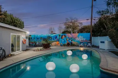 a swimming pool in front of a building with a mural at Blue Haven Solar Pool Heat Parking Billiards in Long Beach