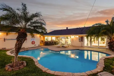 a swimming pool with a palm tree in front of a house at Sunny Daze - Heated Pool - Billiards - Games in Placentia