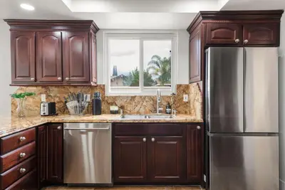 a kitchen with wooden cabinets and a stainless steel refrigerator at Sunny Daze - Heated Pool - Billiards - Games in Placentia