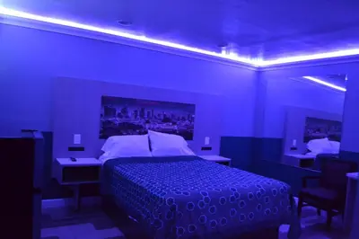 a blue room with a bed and a table and chairs at Villa Las Palmas Motel in Barton Heliport