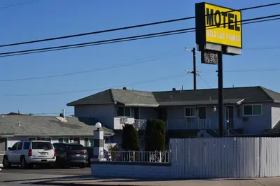 a sign for a motel with cars parked in a parking lot at Villa Las Palmas Motel in Barton Heliport