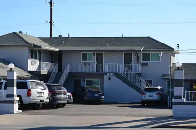a blue house with cars parked in a parking lot at Villa Las Palmas Motel in Barton Heliport