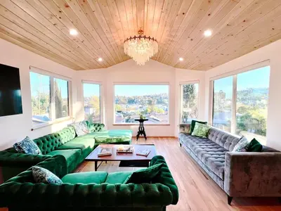 a living room with green couches and a chandelier at The Perch- Hilltop Bungalow, Eagle Rock-near DTLA in Los Angeles