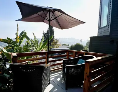 a patio with an umbrella and two chairs on a deck at The Perch- Hilltop Bungalow, Eagle Rock-near DTLA in Los Angeles