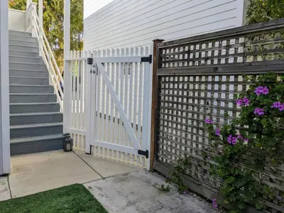 a white fence next to a house with purple flowers at Venice Canals & Beach Guest Suite in Los Angeles
