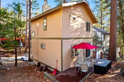 a small house with a table and a red umbrella at Charming Cabin for Winter and Water Sports Fans Near Big Bear Lake, California in Arrowbear Lake