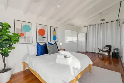 a bedroom with a large white bed with blue pillows at Overlooking Luxury - Pool Heat - Spa - Games in Pico Rivera
