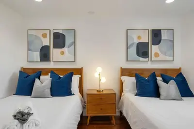 two beds with blue and white pillows in a bedroom at Overlooking Luxury - Pool Heat - Spa - Games in Pico Rivera